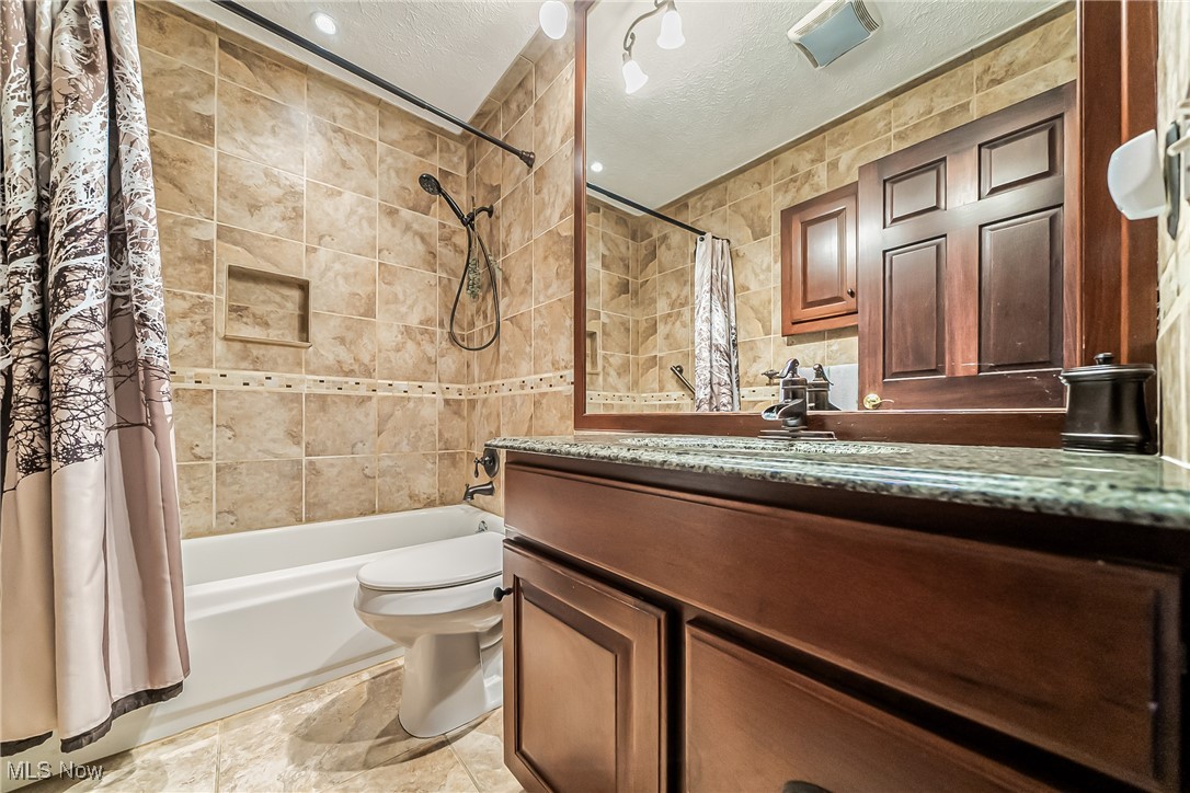 43385 Kipton Nickle Plate Road Lagrange, OH 44050 - Photo 18 of 37 Full bathroom with toilet, vanity, tile patterned floors, a textured ceiling, and shower / tub combo with curtain