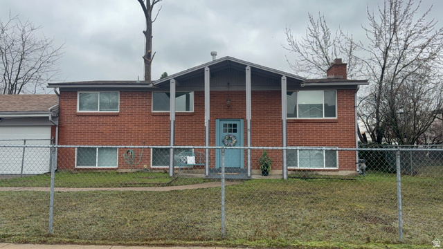 Back of house with a garage, a chimney, and brick siding