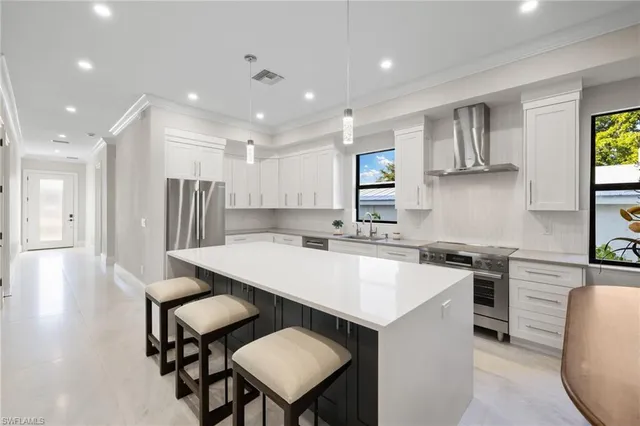 a large kitchen with stainless steel appliances a stove a sink a refrigerator and chairs