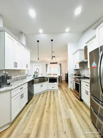 a large kitchen with granite countertop a large counter top appliances and cabinets