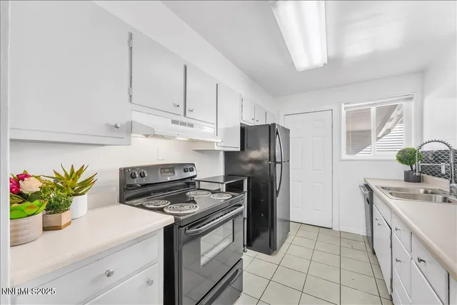 a kitchen with stainless steel appliances a sink a stove a refrigerator a counter space and cabinets