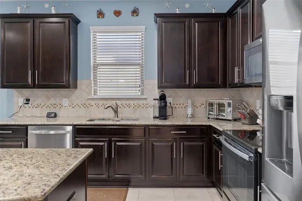a kitchen with stainless steel appliances granite countertop a stove refrigerator sink and cabinets
