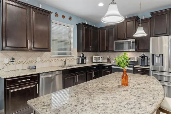 a kitchen with kitchen island granite countertop a sink a stove and refrigerator