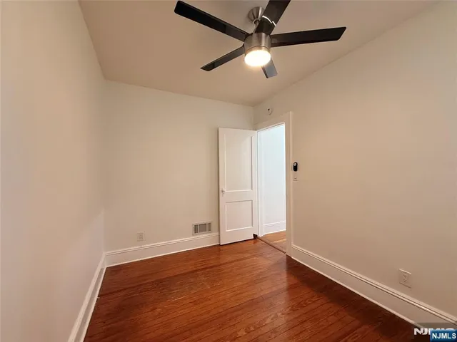 an empty room with wooden floor and ceiling fan