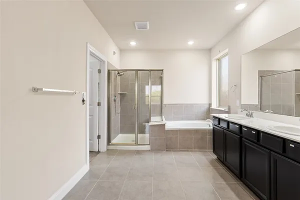 a bathroom with a tub sink shower and two mirror