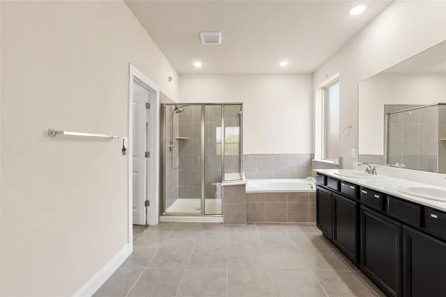 a bathroom with a tub sink shower and two mirror