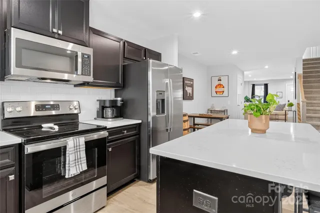 a kitchen with stainless steel appliances granite countertop a stove a microwave a sink a refrigerator and cabinets