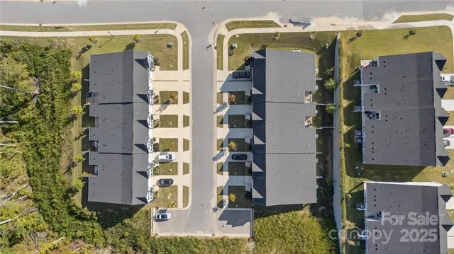 an aerial view of residential houses with outdoor space and parking