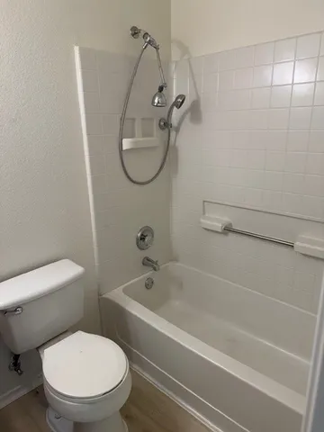 a white toilet sitting next to a bath tub