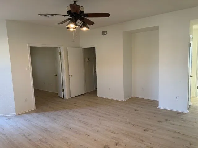 a view of an empty room and chandelier fan