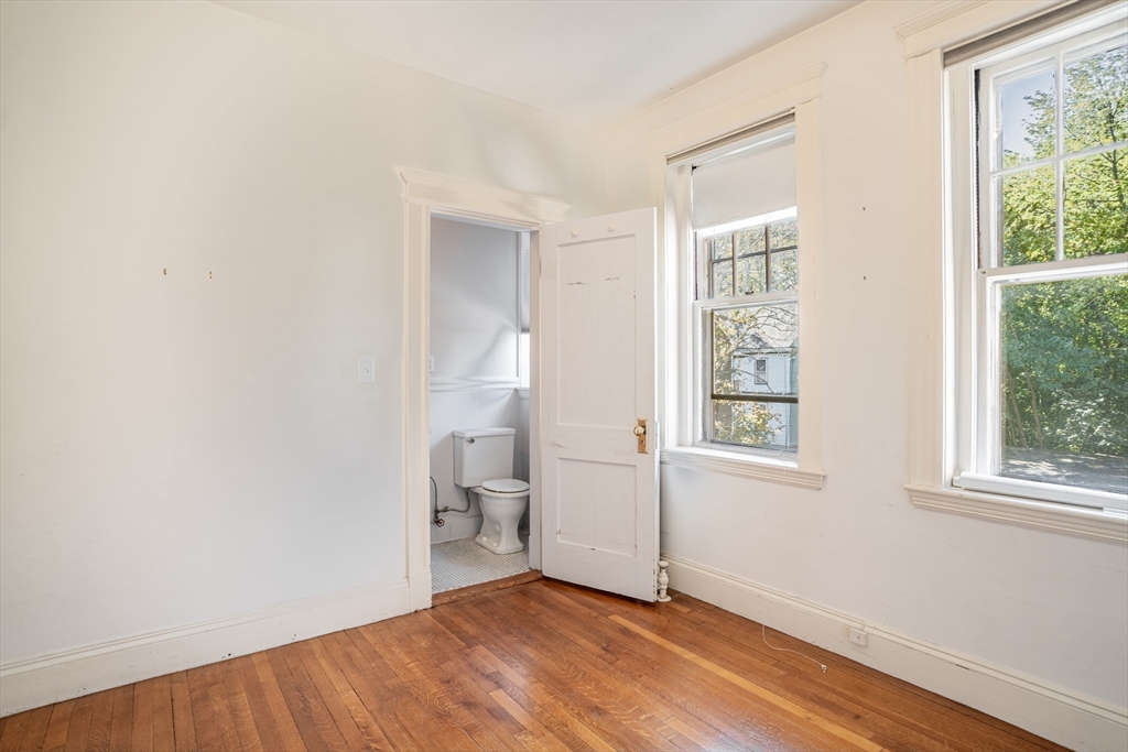 12 Gibbs Street, Unit 2 Brookline, MA 02446 - Photo 11 of 21 a view of an empty room with a window and wooden floor