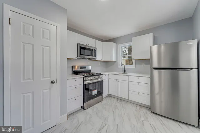 a kitchen with cabinets stainless steel appliances and a window