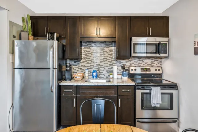 a kitchen with stainless steel appliances granite countertop a refrigerator a stove a sink dishwasher and microwave oven