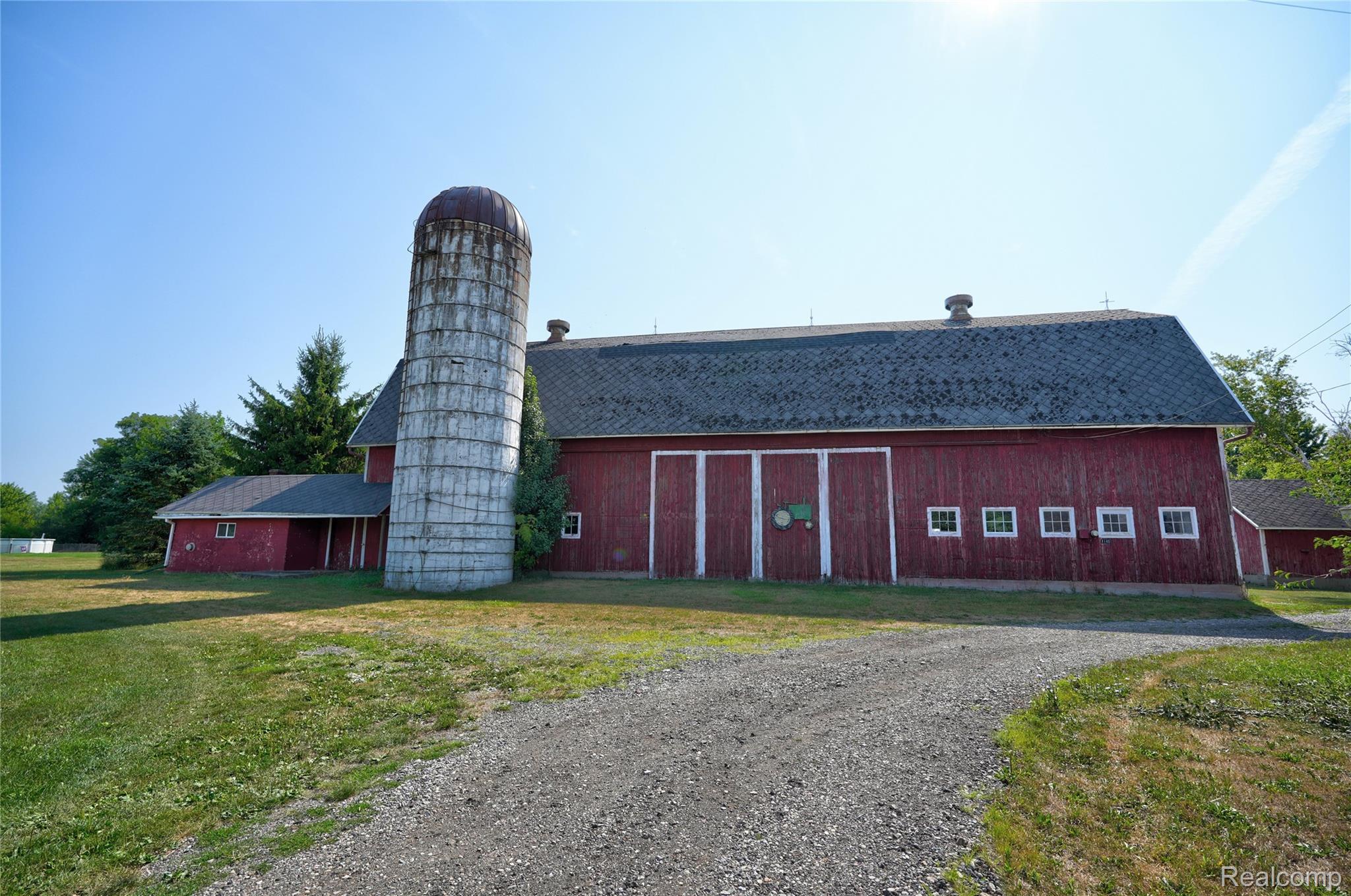 1175 South Morrish Road Flint, MI 48532 - Photo 9 of 72 Red-painted barn structure featuring a prominent silo, multiple large entry doors, and a series of small windows