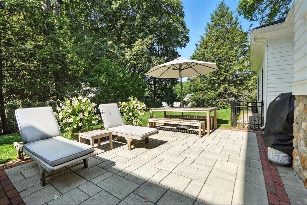 15 Winthrop Road Lexington, MA 02421 - Photo 36 of 39 a view of a patio with a table and chairs under an umbrella with a barbeque grill and a small yard