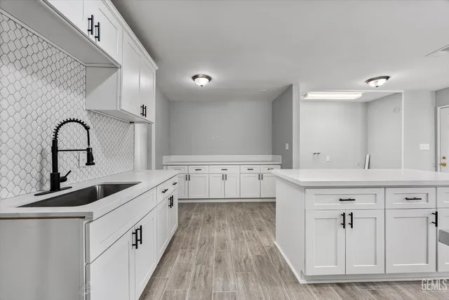 a kitchen with white cabinets a sink and appliances