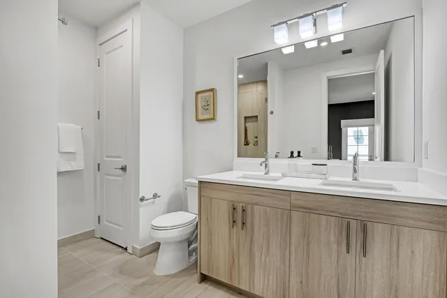 a bathroom with a double vanity sink toilet and mirror