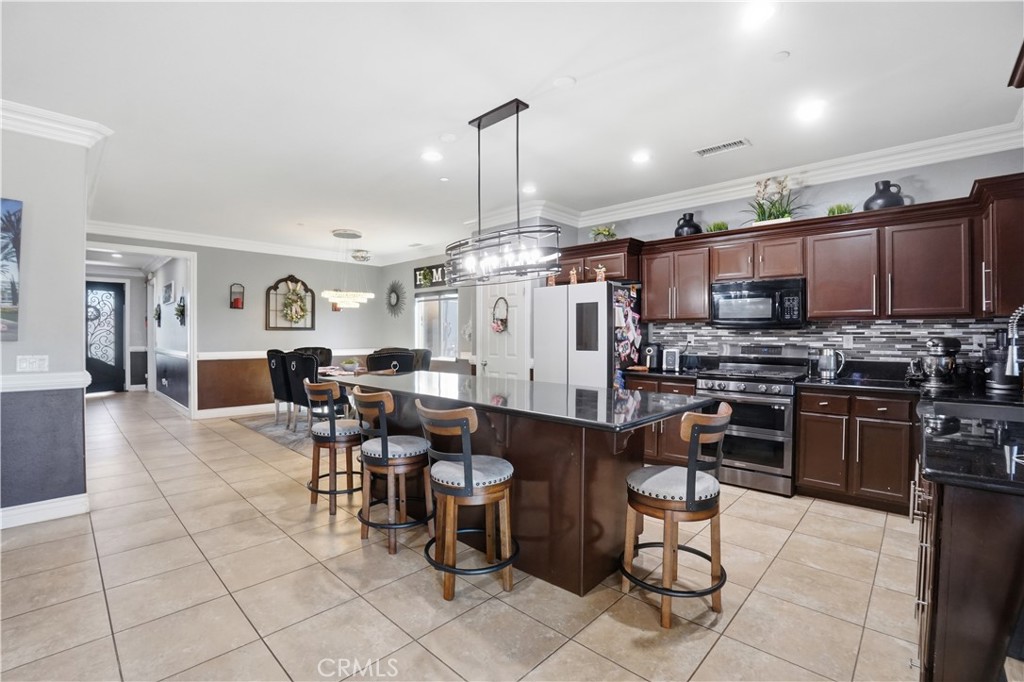 4415 Bethel Road Jurupa Valley, CA 92509 - Photo 21 of 65 a kitchen with stainless steel appliances kitchen island granite countertop a refrigerator a stove a dining table and chairs with wooden floor