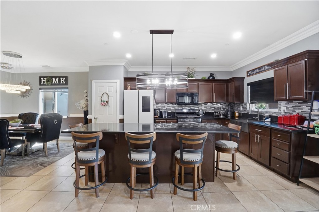 4415 Bethel Road Jurupa Valley, CA 92509 - Photo 60 of 65 a kitchen with stainless steel appliances kitchen island granite countertop a dining table chairs refrigerator and sink