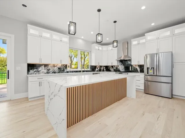 a kitchen with kitchen island granite countertop a sink a counter space appliances and cabinets
