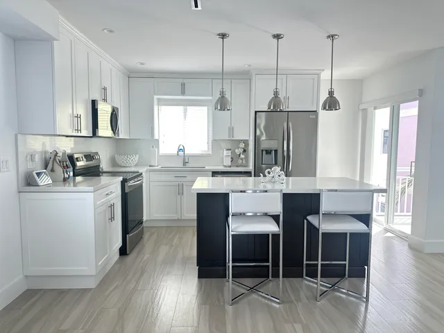 a kitchen with stainless steel appliances kitchen island granite countertop a stove a sink and a refrigerator