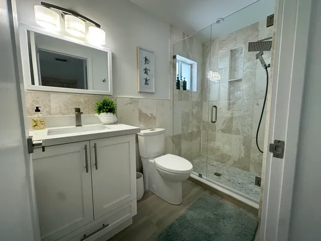 a bathroom with a toilet sink a mirror and shower