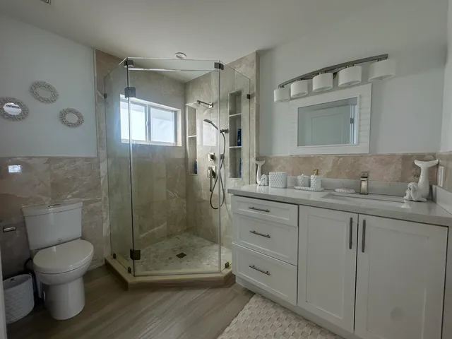 a bathroom with a granite countertop sink toilet a mirror and shower