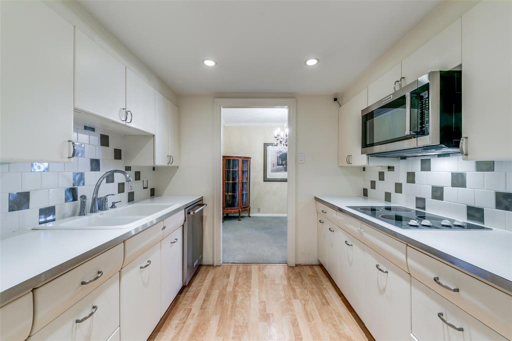 3525 Turtle Creek Boulevard, Unit 3C Dallas, TX 75219 - Photo 15 of 28 Kitchen with light wood-type flooring, light countertops, backsplash, and appliances with stainless steel finishes