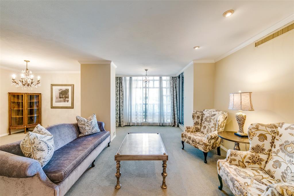 3525 Turtle Creek Boulevard, Unit 3C Dallas, TX 75219 - Photo 8 of 28 Carpeted living room featuring baseboards, an inviting chandelier, and crown molding