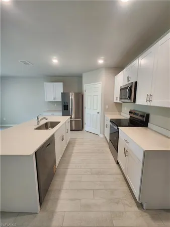 a large kitchen with kitchen island granite countertop a stove top oven a sink dishwasher and a refrigerator with wooden floor