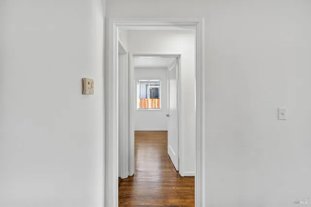 a view of a hallway with wooden floor and a bathroom