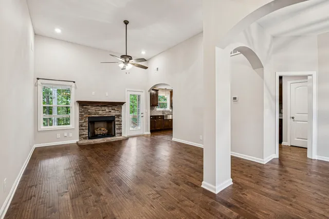 a view of an empty room with wooden floor a fireplace and a window