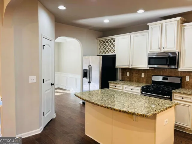 a kitchen with stainless steel appliances granite countertop a refrigerator a stove and a sink