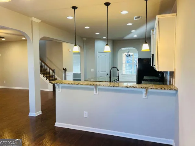 a view of a kitchen with kitchen island stainless steel appliances room with wooden floor