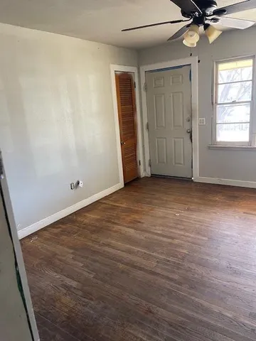 an empty room with wooden floor fan and windows