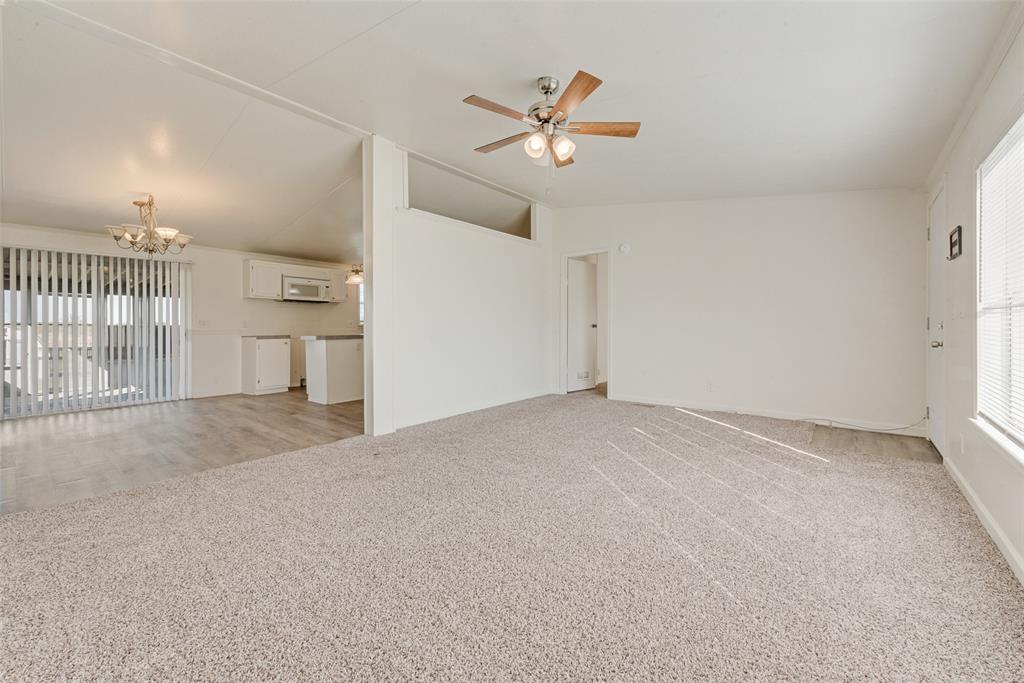 817 Kaufman Street Rosser, TX 75158 - Photo 7 of 29 Unfurnished living room featuring light colored carpet, vaulted ceiling, a chandelier, and ceiling fan