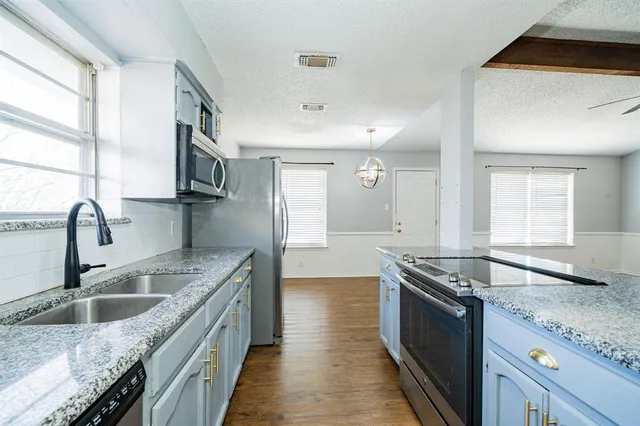 a kitchen with granite countertop a sink stove and cabinets