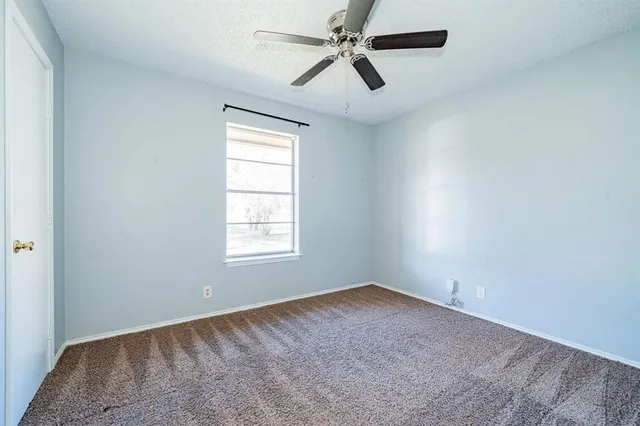 an empty room with a window and a fan