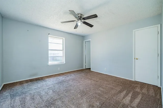 a view of an empty room with a ceiling fan and window