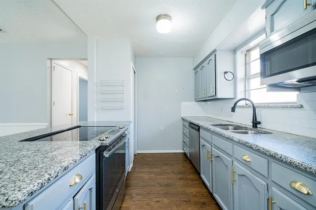 a kitchen with granite countertop stainless steel appliances a sink and a counter space