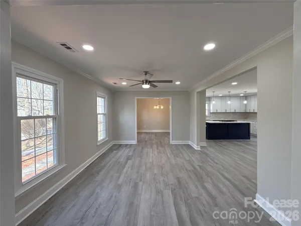 a view of an empty room with wooden floor and a window