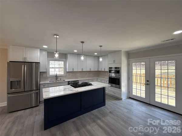 a kitchen with stainless steel appliances granite countertop a refrigerator a sink a stove and oven with wooden floors