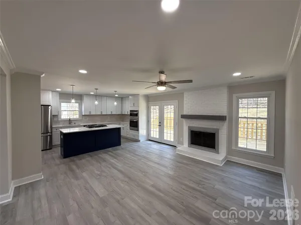 a large white kitchen with a stove a sink dishwasher and a fireplace with wooden floor