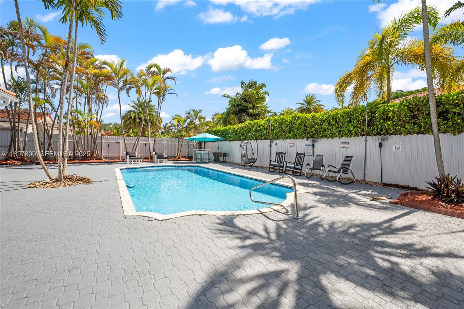 5750 Southwest 67th Avenue Miami, FL 33143 - Photo 58 of 62 a view of a swimming pool with a lawn chairs under palm trees