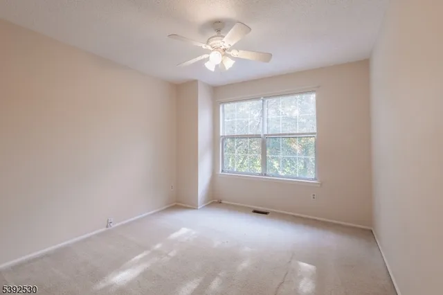 an empty room with windows and chandelier fan
