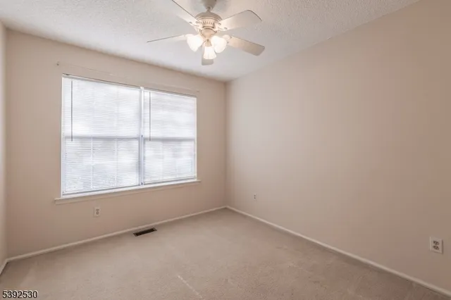 an empty room with a window and a fan