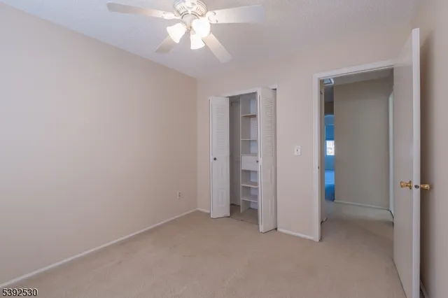 an empty room with closet and a chandelier fan