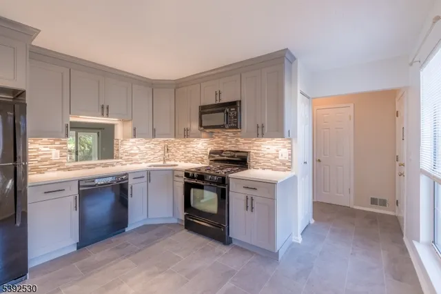 a kitchen with stainless steel appliances granite countertop a stove top oven a sink and a refrigerator