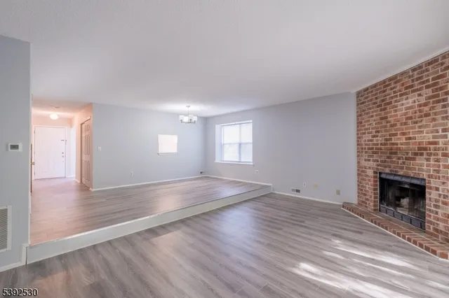 an empty room with wooden floor and fireplace