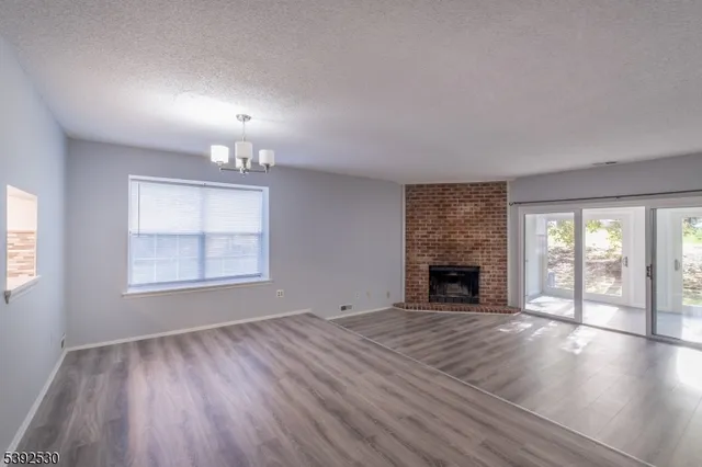 an empty room with windows fireplace and wooden floor